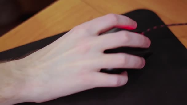 Junge männliche Spielerhand auf Computermaus bewegt sich in Zeitlupe auf schwarzem Mauspad — Stockvideo