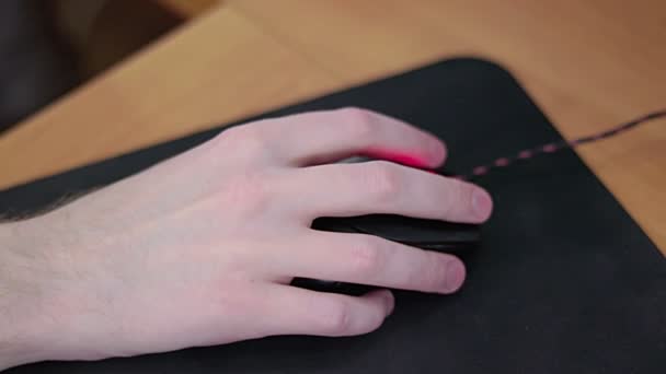Mão gamer macho jovem no mouse do computador em movimento lento na almofada do mouse preto — Vídeo de Stock