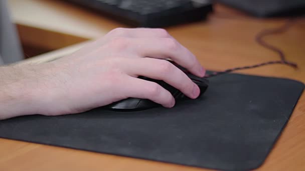 Mão gamer macho jovem no mouse do computador em movimento lento na almofada do mouse preto — Vídeo de Stock