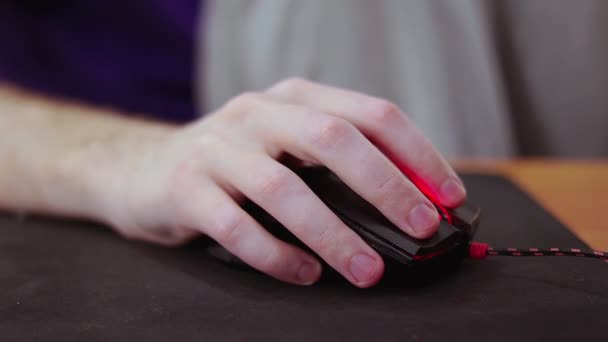 Dettagliato primo piano sul giovane giocatore maschio mano sul mouse del computer sul tappetino nero del mouse — Video Stock