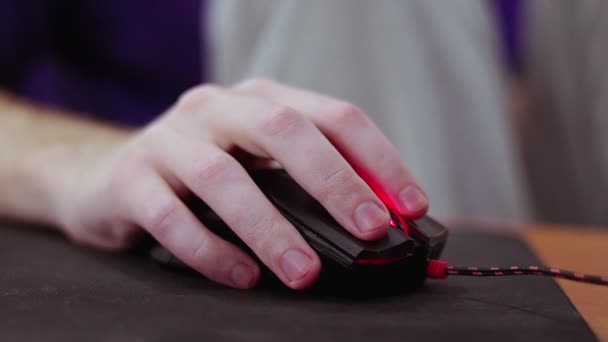 Dettagliato primo piano sul giovane giocatore maschio mano sul mouse del computer sul tappetino nero del mouse — Video Stock