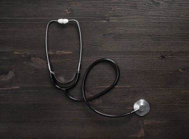 Ahşap masa arka planında tıbbi steteskop. Düz yatıyordu.