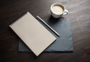 Boş Kraft eskiz defteri, taş tahtada kalem ve kahve fincanı. Tepkili tasarım modeli.