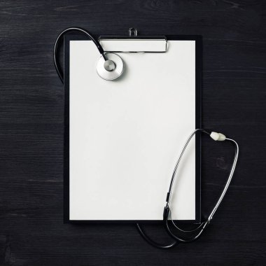 Ahşap masa zemininde steteskop olan boş bir dosya. Üst Manzara. Düz yatıyordu.