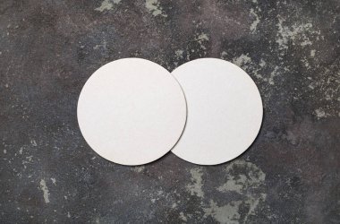 Beton arka planda boş beyaz bira altlıkları. Tepkili tasarım modeli. Düz yatıyordu.