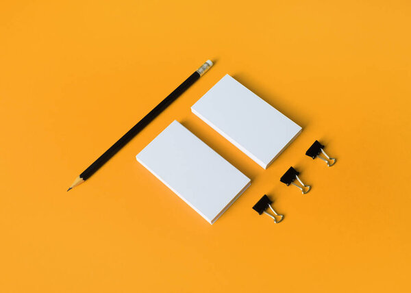 Photo of blank business cards and pencil on yellow background. Stationery mock up.