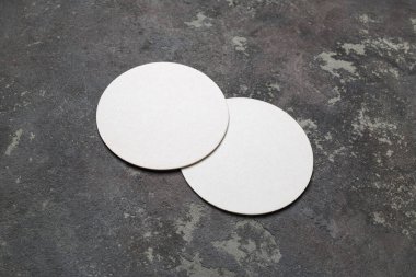 Beton arka planda iki beyaz bira altlığı. Tepkili tasarım modeli.
