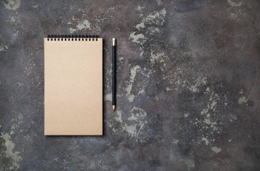 Beton zemin üzerinde boş bir Kraft eskiz defteri ve kalemin fotoğrafı. Uzayı metin için kopyala. Düz yatıyordu.