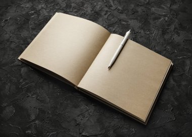 Siyah taş zemin üzerinde boş el işi kağıt çizim defteri ve kalem. Damgalama modeli.