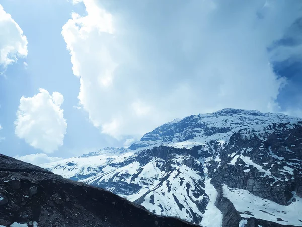 Dağın tepesinde donmuş kar ve dağın tepesinde beyaz bulutlar.