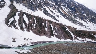 Karla kaplı bir dağdan akan su nehri. Seçici odak