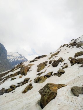 Karla kaplı dağ sıraları. Şimdi dağlarla kaplı tepeler. Kayalık kayaların üzerindeki bulutlar. Karda terk edilmiş dağ zirveleri. Resimli dağ manzarası.