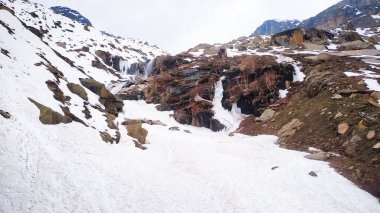 Karla kaplı dev kayalar. Karlı dağlardan çıkıntılar. Uçurumlar ve büyük kayalar. Tehlikeli arazi. Dağların gölgesindeki güneş ışınları..