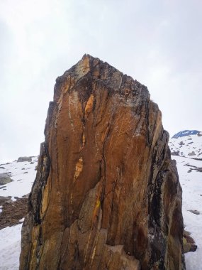 Karlı bir dağın tepesinde güzel, büyük bir taş.