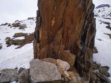 Karlı bir dağın tepesinde büyük bir taş.