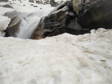 Dağlarda bir şelale. Dağın tepesindeki kar bir taş kadar sağlam..