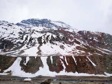 Bulutlu gökyüzüne karşı karla kaplı dağlar