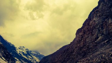 Dağların üstünde dramatik bir gün batımı. Muhteşem günbatımında ya da gün doğumunda engebeli kayalık dağlar.