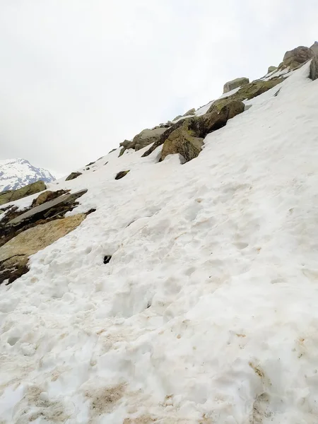 Karla kaplı dağ sıraları. Şimdi dağlarla kaplı tepeler. Kayalık kayaların üzerindeki bulutlar. Karda terk edilmiş dağ zirveleri. Resimli dağ manzarası.