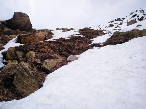 Yaz mevsiminde mavi gökyüzünün önündeki kayalıklarda kar..