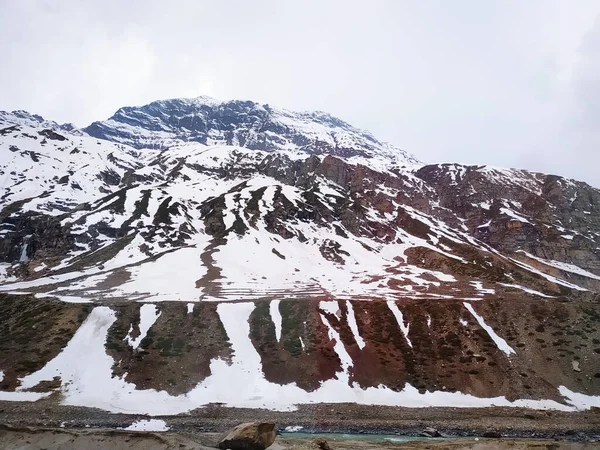 Bulutlu gökyüzüne karşı karla kaplı dağlar