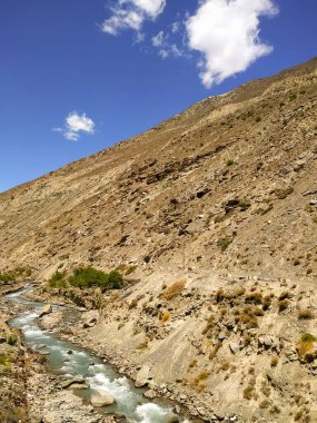 Kum tepelerindeki nehir mavi gökyüzü arka planında beyaz bulutlarla