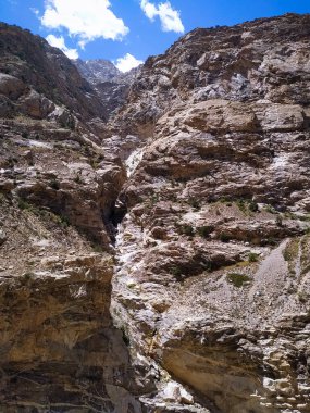 Mavi gökyüzü ve beyaz bulutları olan bir dağ kayası