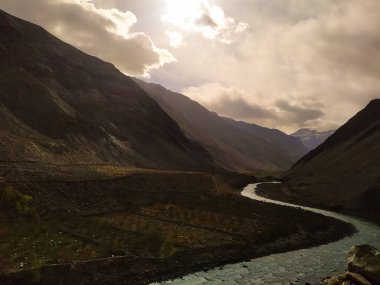 Yüksek Himalaya dağlarıyla manzara, güzel kıvrımlı nehir, bulutlu orman gökyüzü ve Hindistan 'da yaz günbatımında sarı güneş ışığı. Dağ vadisi. Himalayalar 'da seyahat