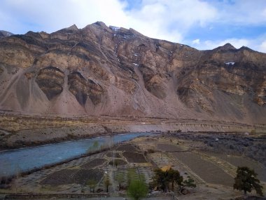 Dağlarda akan nehir, tarlalar ve ağaçlarla