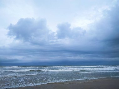 Tropik plajın güzel arkaplan görüntüsü. Okyanusun üzerinde parlak bir yaz güneşi. Açık bulutlu mavi gökyüzü, dalgalı turkuaz okyanus ve temiz kum. Temiz ortamın ahengi. Geniş biçim.