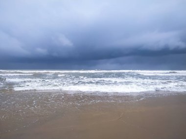 Clear waves on the sand beach with storm sky