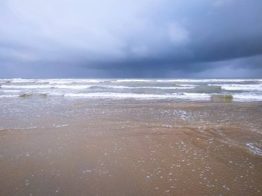Kumsalda bulutlu gökyüzü ile fırtınalı deniz dalgaları