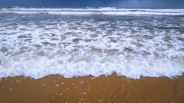 Güzel beyaz dalgalar kumsalda kırılıyor