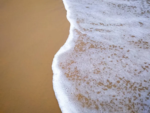 海浪中的白色泡沫在低潮时轻柔地在沙滩上移动 — 图库照片