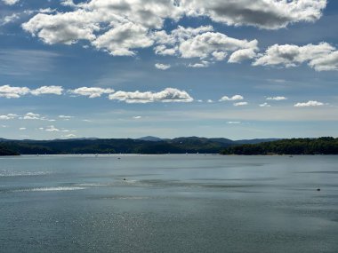 Solinie Gölü üzerinde hafif bulutlu bir hava var Bieszczady Dağları 'nın tepeleri kozalaklı ormanlarla kaplı.