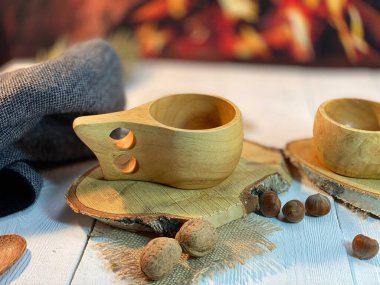 Ahşap bardak altlığı yerde ve şöminenin yanındaki beyaz masanın üzerinde fındıkla saçılmış, kahve için ahşap bardaklar var.