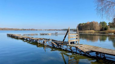 Wlodawa yakınlarındaki Biale Gölü, tahtadan yapılmış eski bir iskele, mavi gökyüzü, berrak su.