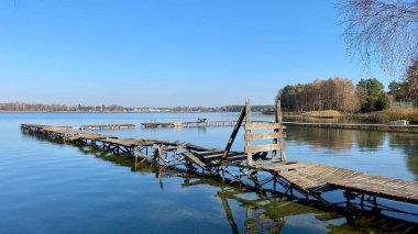 Wlodawa yakınlarındaki Biale Gölü, tahtadan yapılmış eski bir iskele, mavi gökyüzü, berrak su.