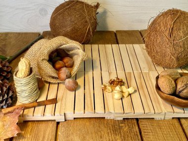 Hindistan cevizi cevizi ve fındıklar, çam ağacından yapılmış samanların arka planındaki meşe ağacından yapılmış samanların arka planında bulunan paletlerin üzerinde yatar.