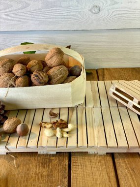 ceviz ve fındıklar bir sepetin içinde, meşe ağacından yapılmış paletlerin üzerinde, arka planda görünen saman yapraklarının üzerinde, çam ağacından beyaza boyanmış.