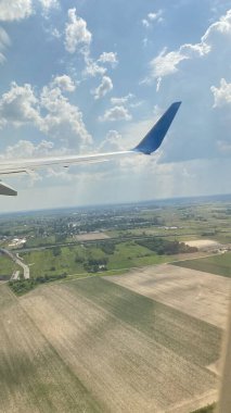 blue sky swirling clouds roads forests and fields on ground view of wing of aircraft