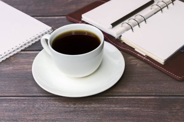 Beyaz bir fincanda, ahşap bir masanın üzerinde, belgelerin arka planında duran kahve. İş sırasında bir mola. iş kavramı