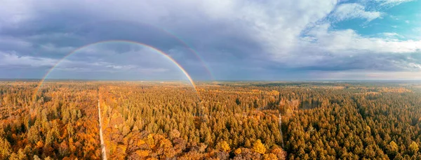 Aerial panorama of an indian summer nature photo with the view over a forest and a impressive full rainbow, just before the rain started. — Stock Photo, Image