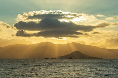 Muhteşem güneş, deniz manzarası gibi büyük bir bulutun içinden düşüyor..