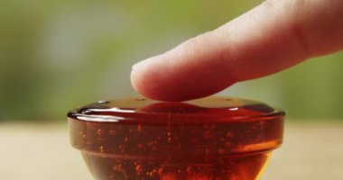 Parmağımı bal kasesine daldırıyorum Yeşil bir arka planda bir Macro Shot