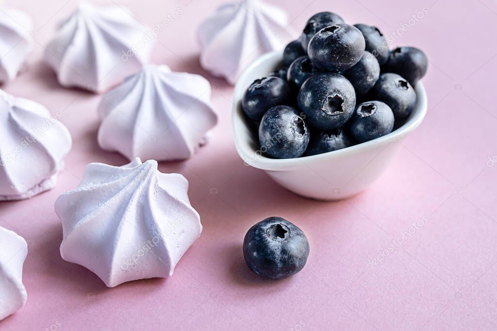 French berry meringue cookies or marshmallow and blueberries in the plate on the table close-up