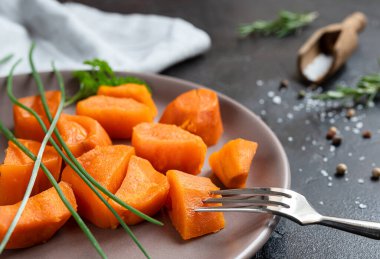 Roasted sweet potatoes with spices on a dark table close-up