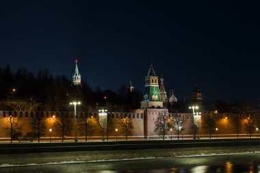Moskova, Rusya. Kremlin 'in gece manzarası: kuleler, duvar, duvarın arkasındaki ağaçlar. St. Arka planda Basil 'in katedrali