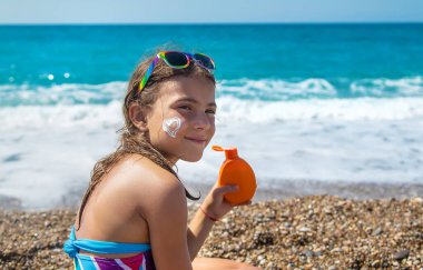 Çocuk yüzüne güneş kremi sürüyor. Seçici odaklanma. Çocuk.