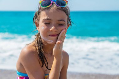 Çocuk yüzüne güneş kremi sürüyor. Seçici odaklanma. Çocuk.